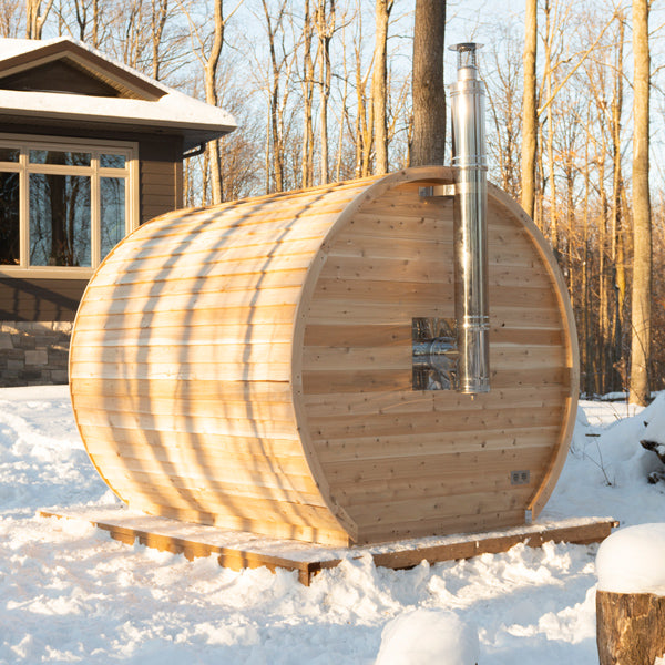 Elation barrel sauna in winter, shown with optional wood heater chimney