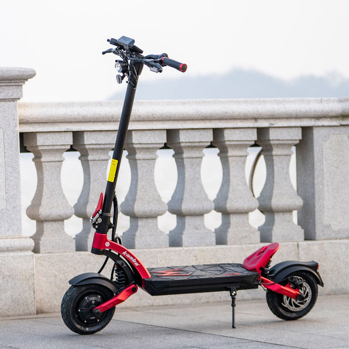 Kaabo Mantis X Plus electric scooter side view with red frame, dual suspension, and 10-inch pneumatic tires, parked outdoors