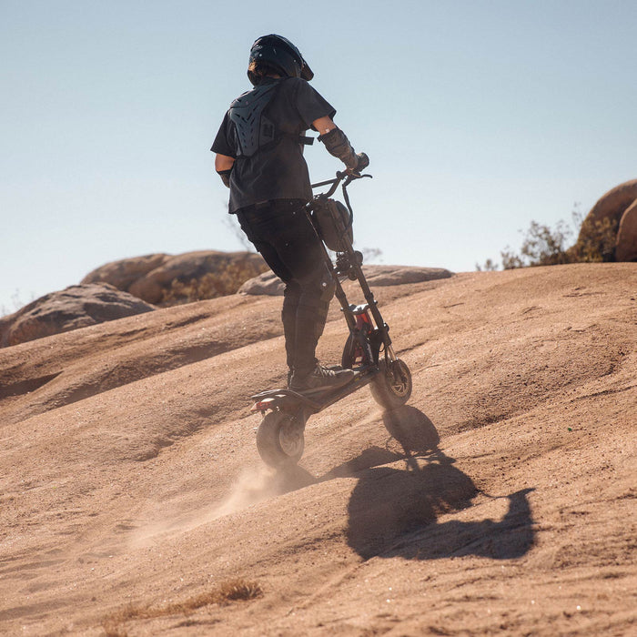 Kaabo Warrior 11 Pro Plus electric scooter climbing a steep rocky hill, showcasing dual motor torque and off-road performance